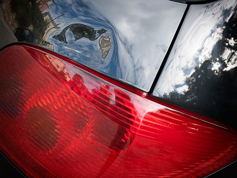 Dented tailgate of a car above the rear light.